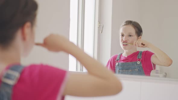 Little girl brushing her teeth in the bathroom in the morning alt