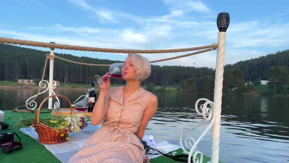 Girl on a Raft on the Lake Drinks Wine From a Glass