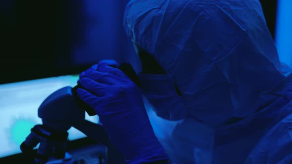 Young scientist working in laboratory examining coronavirus  through microscope alt