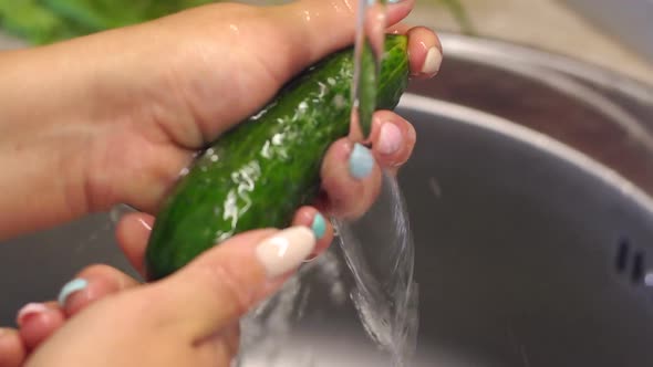 Closeup of a Woman Washing Fresh Cucumbers in the Kitchen Sink alt