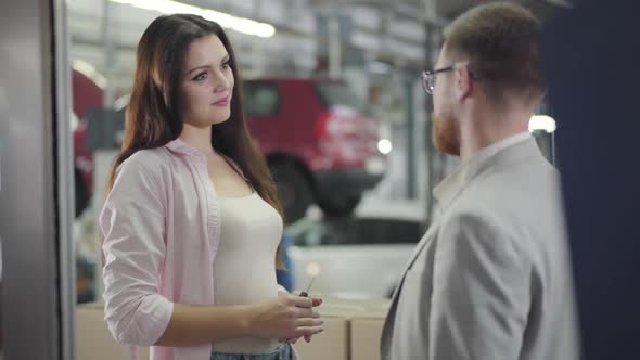 Portrait of Attractive Caucasian Female Car Dealer Giving Keys To the Buyer alt