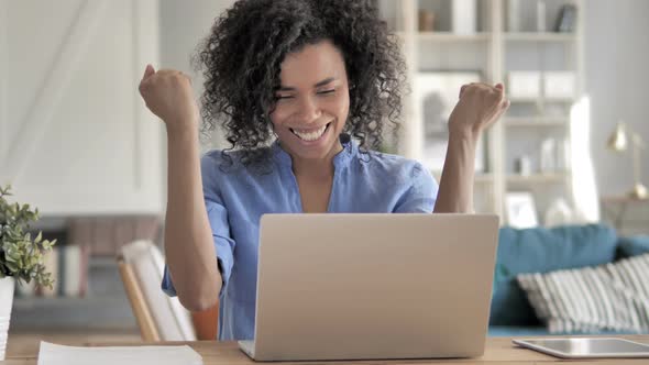 Excited African Woman Celebrating Success on Laptop alt