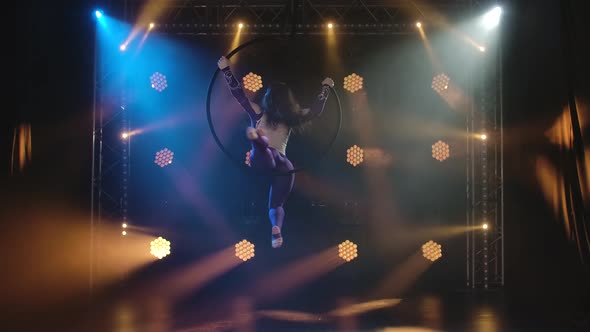 The Young Aerial Artist Woman Rotates Rapidly in an Aerial Circle. Filmed in a Dark Studio with alt