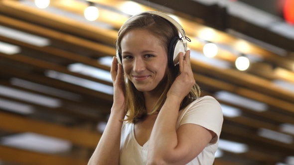 Nice young girl listening to music in headphones smiling alt