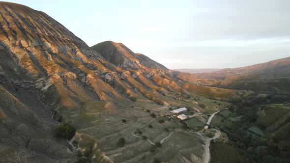 Mountain peaks in the rays of the setting sun, aerial view, a village in canyon