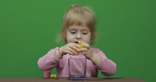 Beautiful Young Girl Squeezes Lemon Juice and Drinks It with a Grimace on Face alt