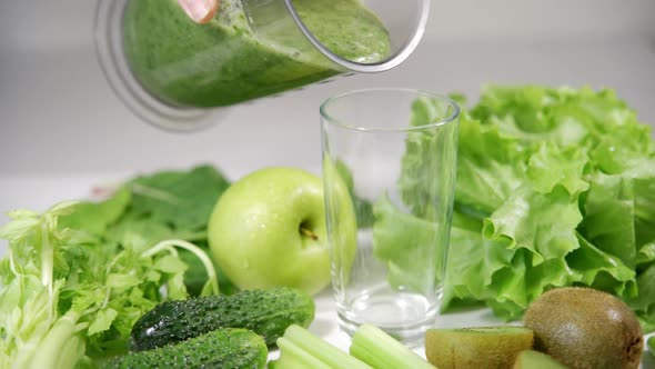 Woman Pouring a Green Detox Juice From Blender to a Glass