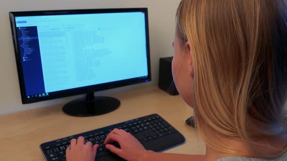 A Woman Sits at a Desk and Works on a Computer alt