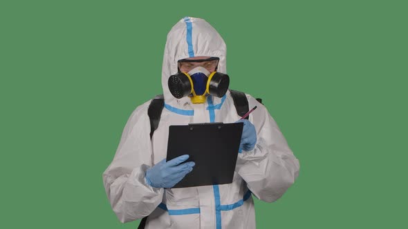 Portrait of a Man in a Protective Suit, Goggles, Gloves and a Respirator Holds a Folder and Marks alt