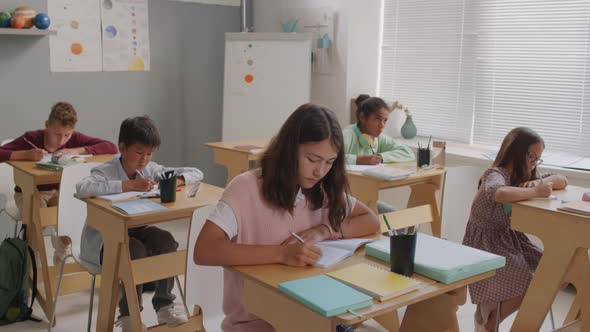 Kids Writing in Notebooks During Lesson alt