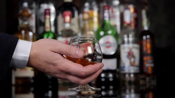 Closeup of a Businessman Holding a Glass of Cognac in a Bar alt