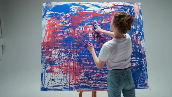 Woman Artist Draws with Her Hands on a Large Canvas in a White Room a Talented Artist Draws a Color alt