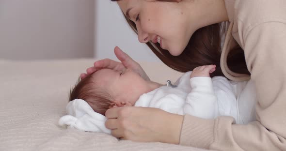 A Caring Mother Takes Care Of A Newborn Baby, Gently Kisses Her And Strokes Her Face