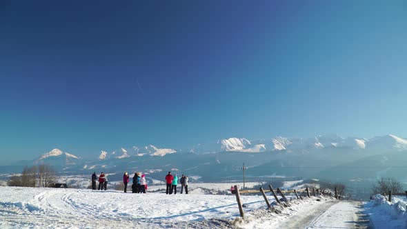Snowy Landscape of Mountains Range with People on Slope in Sunshine Under Clear Blue Sky