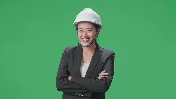 Smiling Asian Female Engineer Crossing Her Arms And Shaking Her Head In The Green Screen Studio alt