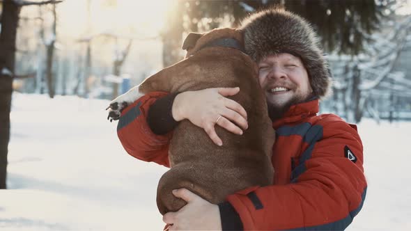 Happy Bearded Man Hugging His Bulldog at Winter Sunny Day alt