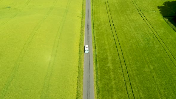 Mini Bus Driving On Narrow Country Road, With Green Fields On Both Sides, Drone Stock Footage X New alt