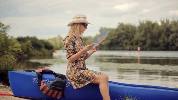 Woman Tourist Sitting On Kayak And Searching Way On Map On Holiday Vacation Trip. alt