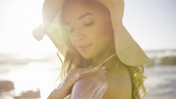 Woman applying sunscreen lotion on the beach 