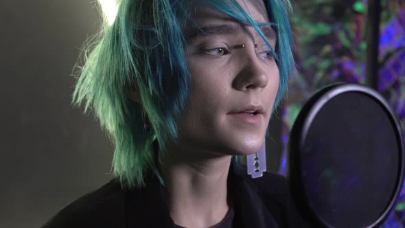 Young Attractive Man with Blue Hair Sings Into a Microphone in a Recording Studio alt