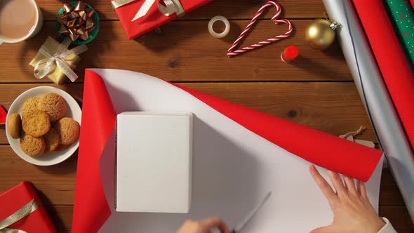 Hands Wrapping Christmas Gift Into Paper at Home alt