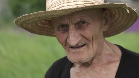 Old Man Wearing Wellworn Straw Hat Looks Straight Closeup