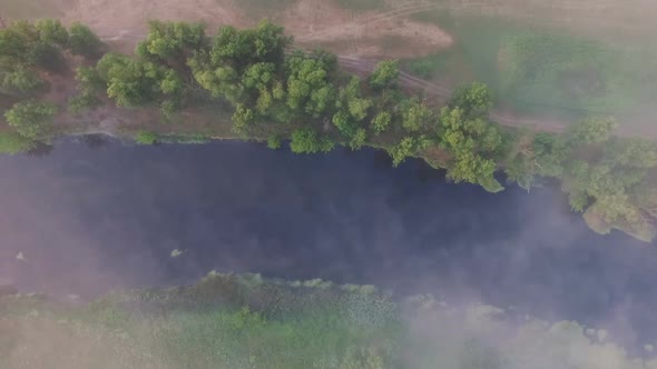 Top-down View Over Little Misty River Streaming Through Valley. Aerial Shot of Beautiful Foggy alt