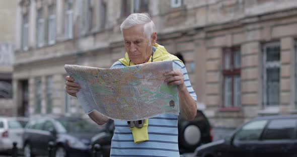 Senior Tourist Exploring Town with a Map. Looking in Binoculars alt
