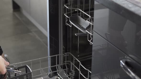 Man in the kitchen removes the clean dishes from the dishwasher alt