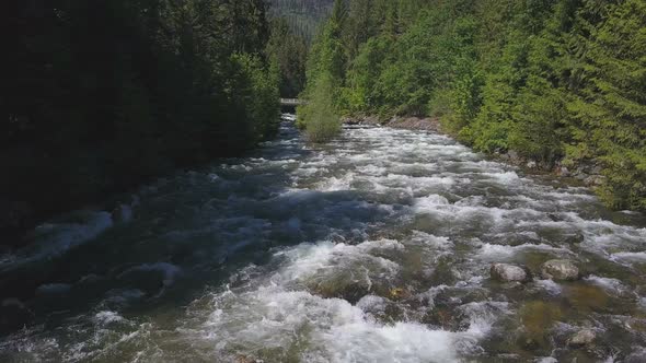 Aerial Drone Traveling Along Water Rapids With Mountains And Evergreen Forest 3