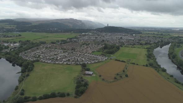 high aerial shot over Stirling flying east, towards the Wallace Monument on a cloudy day alt
