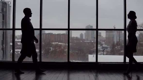 Businessman and Business Woman Meet in the Office Near the Window and Discuss the Project alt