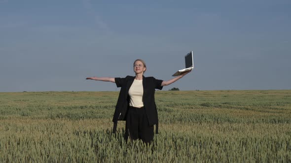 employee of an agricultural firm with a laptop checks the quality of wheat in the field