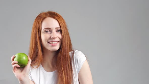 Portrait of Young Redhead Girl Holding Green Apple Looking at Camera and Smiling