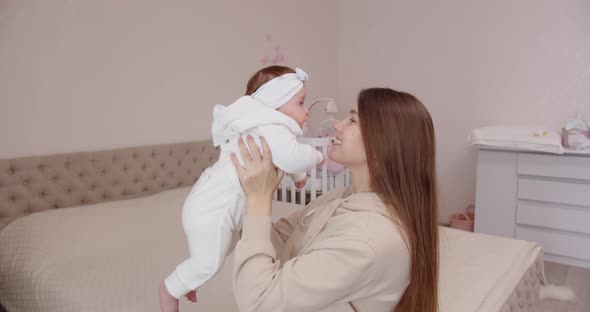 Happy Young Mother Tenderly Caresses And Kisses The Newborn Baby, Holding Her In Her Arms