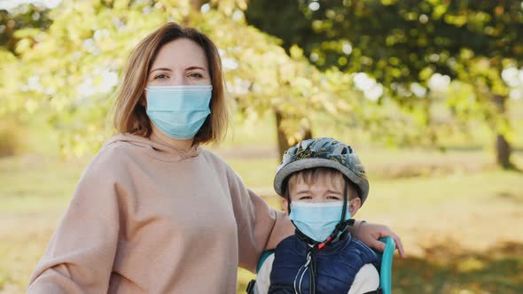 Portrait of Mom and Little Son Wearing Masks Outdoors