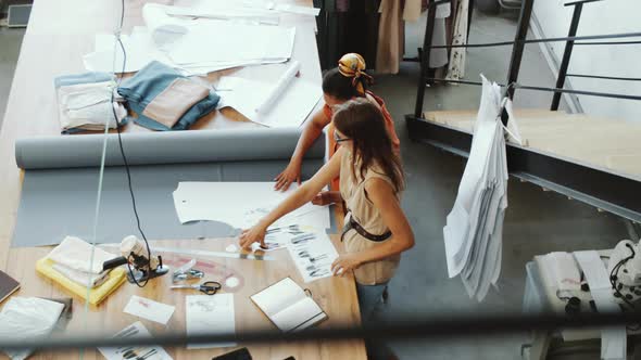 High Angle of Two Female Tailors Discussing Fashion Sketches in Studio alt