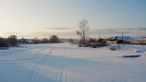 Countryside landscape at sunset; snow-covered hamlet in winter, Ural