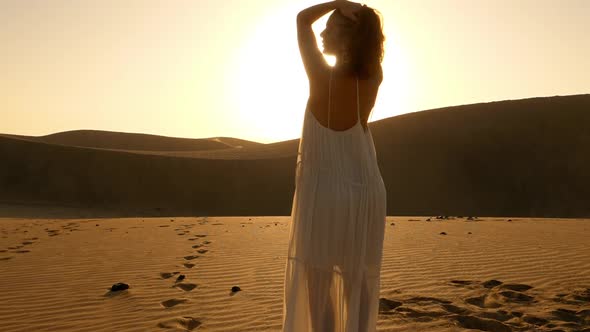 Beautiful Model Standing with Flare of the Sun in the Background Along the Dunes alt