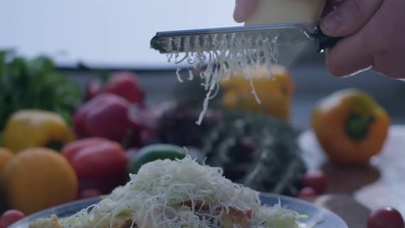 Closeup of Hard Cheese is Grated on a Small Grater Holding in Hands alt