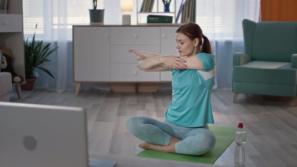 Woman in Sportswear Leads a Sporty Lifestyle and Exercises with an Online Instructor While Sitting alt