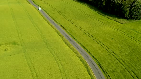 Mini Bus Driving On Narrow Country Road, With Green Fields On Both Sides, Drone Stock Footage 3 alt