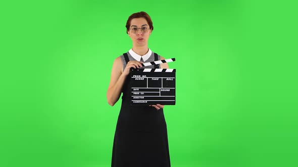 Funny Girl in Round Glasses Is Holding a Movie in Her Hands. Green Screen alt