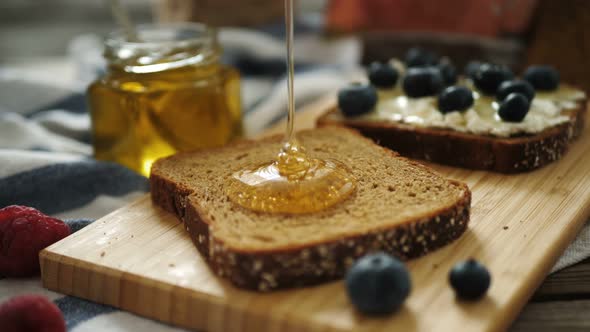 Clear Liquid Honey Pouring on a Piece of a Black Rye Bread. Close Up. Seamless Cinemagraph