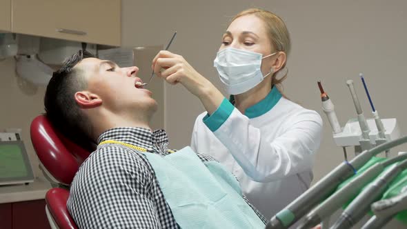 Female Dentist Examining Teeth of Her Patient, Working at Dental Clinic alt