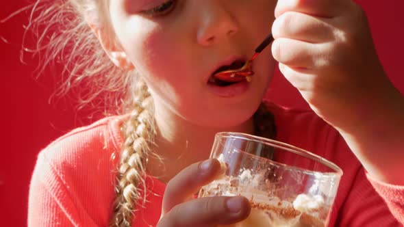 Child eating yogurt jelly pink background. Dairy product diet Lactobacillus Acidophilus
