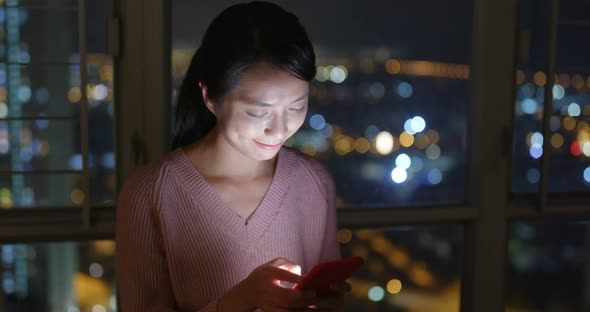 Woman look at mobile phone at night inside living room