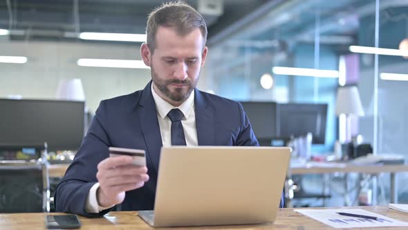 Successful Young Businessman Using Credit Card on Laptop alt