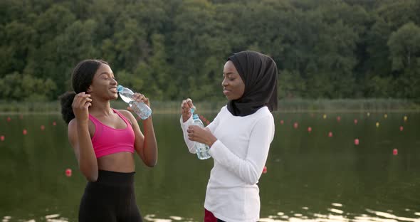 Black Female Friends Drinking Water After Running in Summer alt