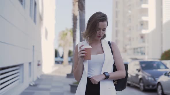 Young Entrepreneur Drinking Coffee and Checking Emails on Smartwatch Outdoors